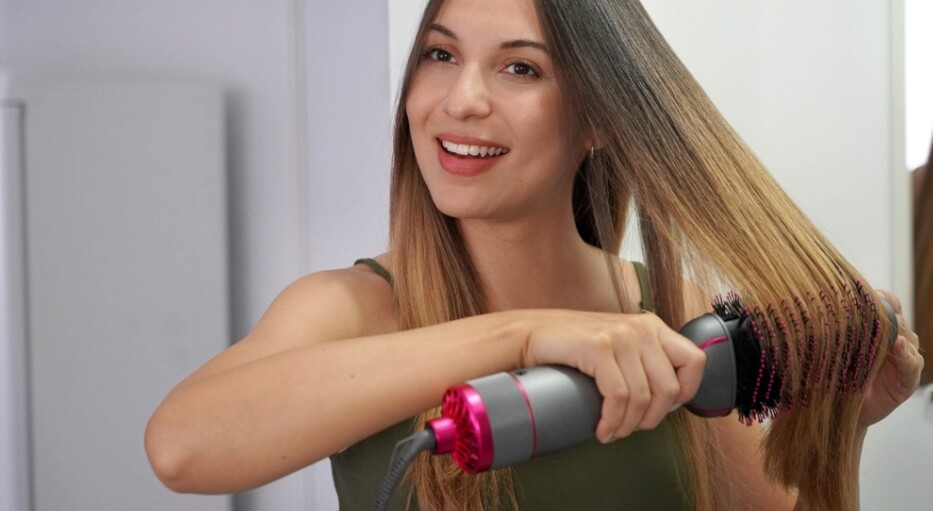 mulher alisando o cabelo com uma escova alisadora