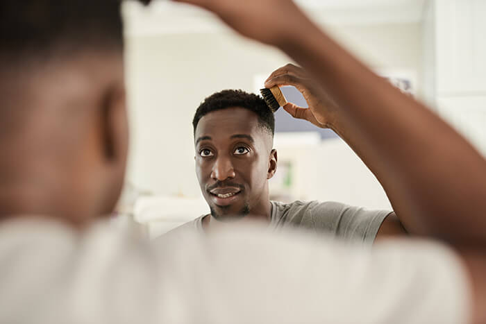 homem negro, em frente ao espelho, escovando o cabelo