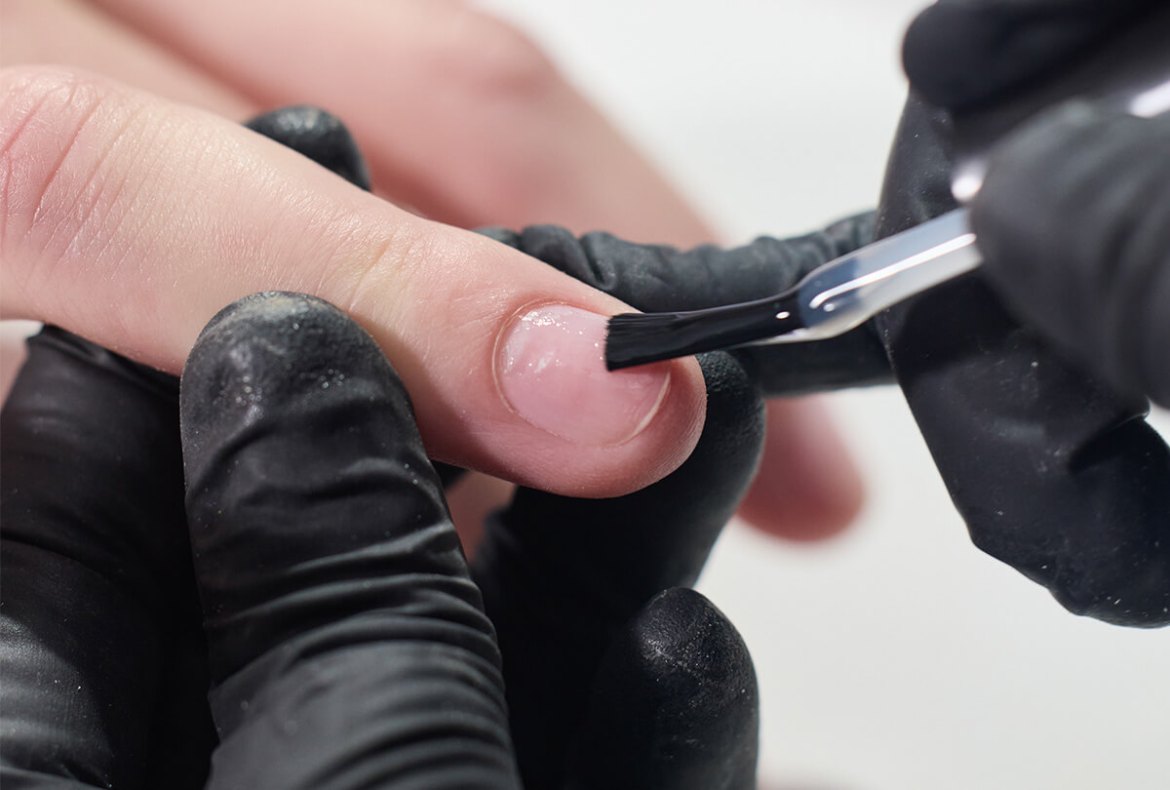 nail designer aplicando produto na unha natural da cliente para unhas de gel