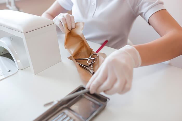 manicure abrindo envelope com alicate e tesoura esterilizados em autoclave